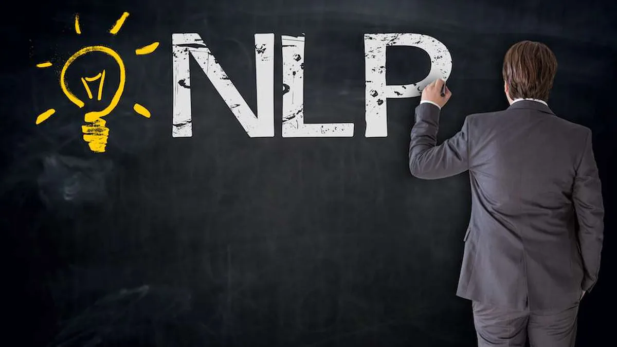 Ein Mann schreibt „NLP“ mit Kreide an eine Tafel